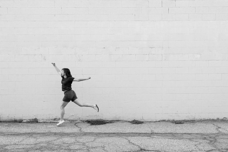 black and white photo of woman leaping on cracked asphalt